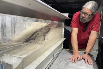 Lead centrifuge technician Clint Barela evaluates the results of a levee failure test on the platform of the US Army's large beam centrifuge